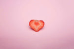 Alt Tag: Heart-shaped strawberry slice on pastel pink background illustrating sweetness in a vintage wind up dolls themed article cover