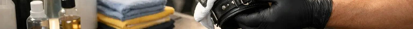 Close-up of various BDSM restraints including leather cuffs and metal chains being cleaned with a soft cloth and mild soap