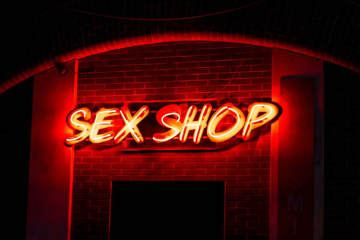 Neoonreklaam “SEX SHOP” pimedal tänaval – Enjoy The Moment võrgukeha erootikapoodide visuaalne bränding