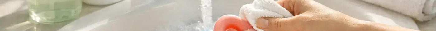 Hands washing a silicone sex toy with mild soap and water for safe cleaning