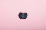 Black kidney-shaped stone on a pink background, perfect for decorative use.