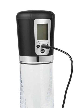 An automatic penis pump with a black base, clear cylinder, and LCD screen, plugged into a charging cable.