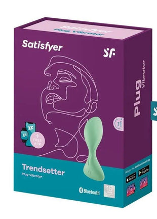 Butt Plug with Vibration in pale green silicone, shown beside purple and teal Satisfyer Trendsetter packaging.