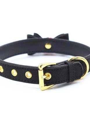 Collar with Bow and Rattle, black leather-style strap with gold-tone studs, buckle and ring; bow visible behind.