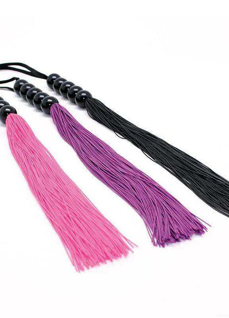 Flogger Silicone Pink with long bright pink strands, alongside purple and black versions with beaded handles.