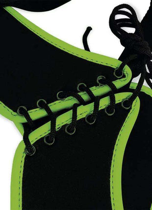 Strap-on harness in black material with bright neon green trim, metal eyelets and black crisscross lacing