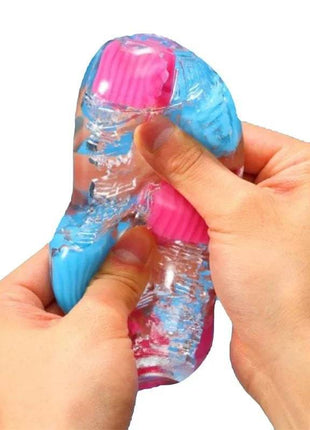 Masturbator Bobble Crazy Cubes in translucent blue elastomer with bright pink cube-textured inserts, squeezed by hands