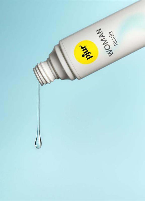 Pjur Woman Nude water-based lubricant in a white tube with yellow logo, dispensing a clear gel drop