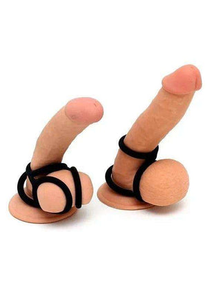 Quatro Cock Ring four-ring ball splitter in black elastic material, shown fitted around two flesh-toned penis and testicle forms