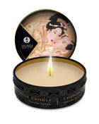 Shunga Mini Vela de Masaje Vanille massage candle in a black round tin with gold details and a lit wick